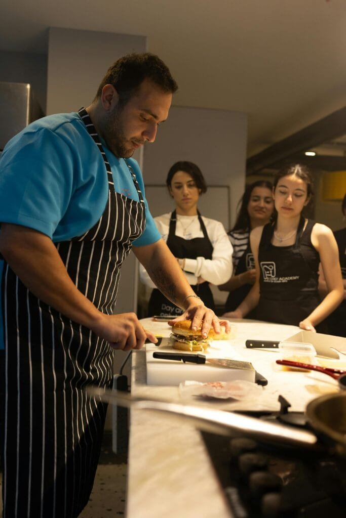 Home 1 A chef teaches a cooking class in Samsun, Türkiye, demonstrating precise burger preparation.