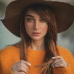 Private Tours (3 to 4 hours) 3 Elegant portrait of a woman in a hat and sweater outdoors in Paris.