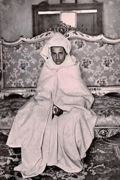 A historical photo of King Mohammed V seated on the royal throne in traditional Moroccan attire, reflecting his dignified posture and role as a key figure in Morocco’s independence movement.