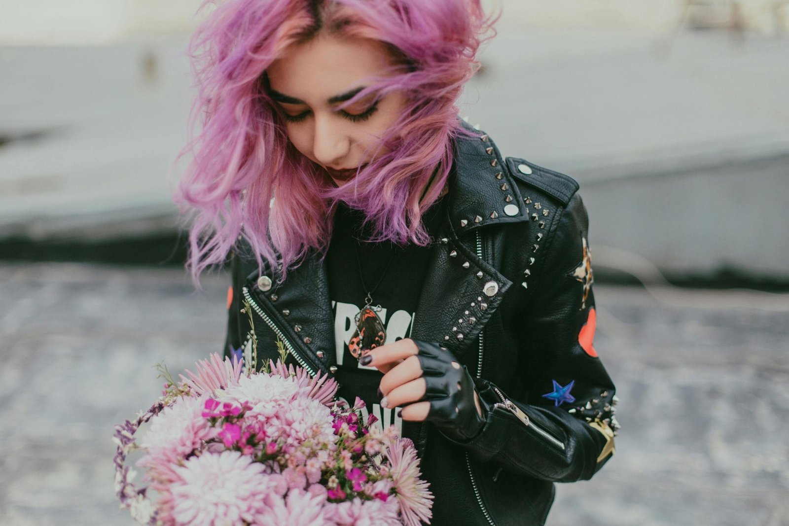 Guesthouse in the city of Fez. 30 A stylish young woman with purple hair holding a bouquet, wearing a black leather jacket outdoors.