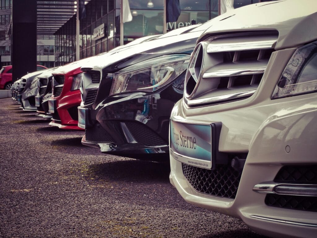 Car Rental Services 2 Luxury cars lined up at an outdoor dealership, showcasing sleek designs.