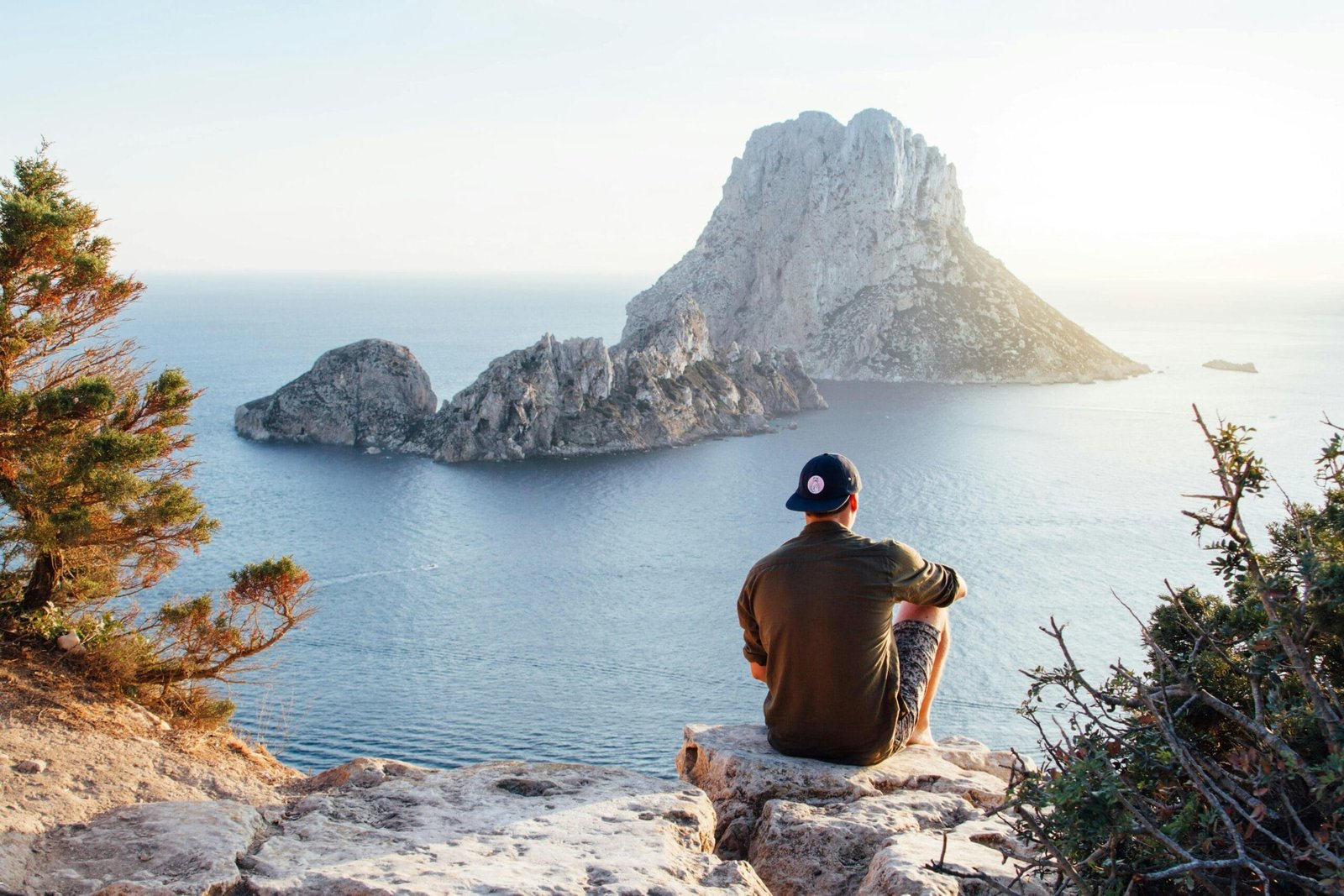 Discover a comfortable journey from Fes to Chefchaouen 8 Man enjoys a scenic view of Es Vedrà at sunset from a cliff in San Juan Bautista, providing a perfect summer escape.