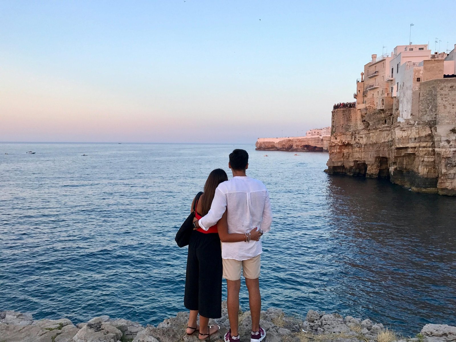 Group Tours (5 to 6 hours) 3 Couple embraces by the sea in Polignano A Mare, Italy, during sunset.