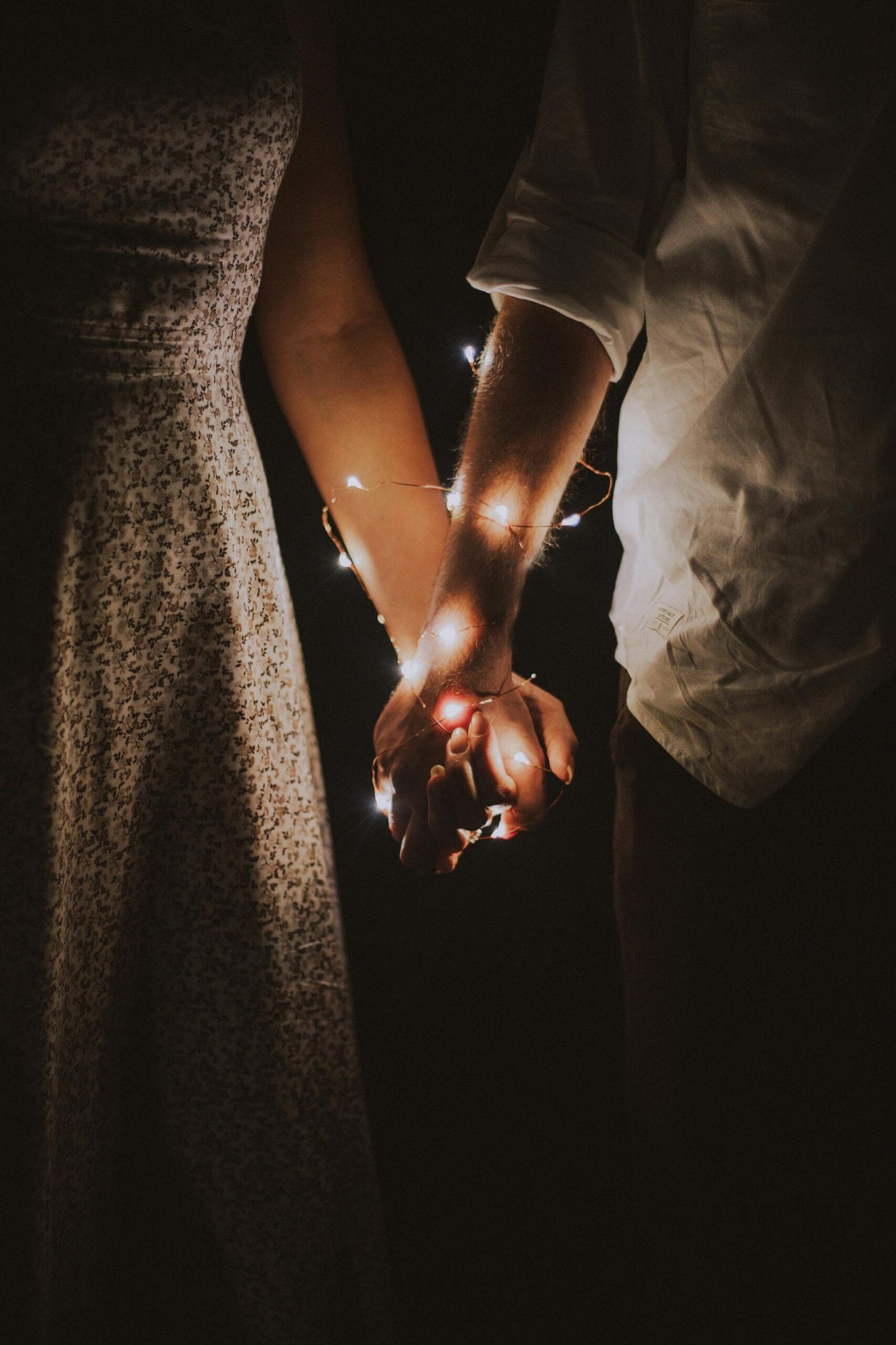 Airport Transfers 3 A warm and intimate close-up of a couple holding hands adorned with glowing string lights.