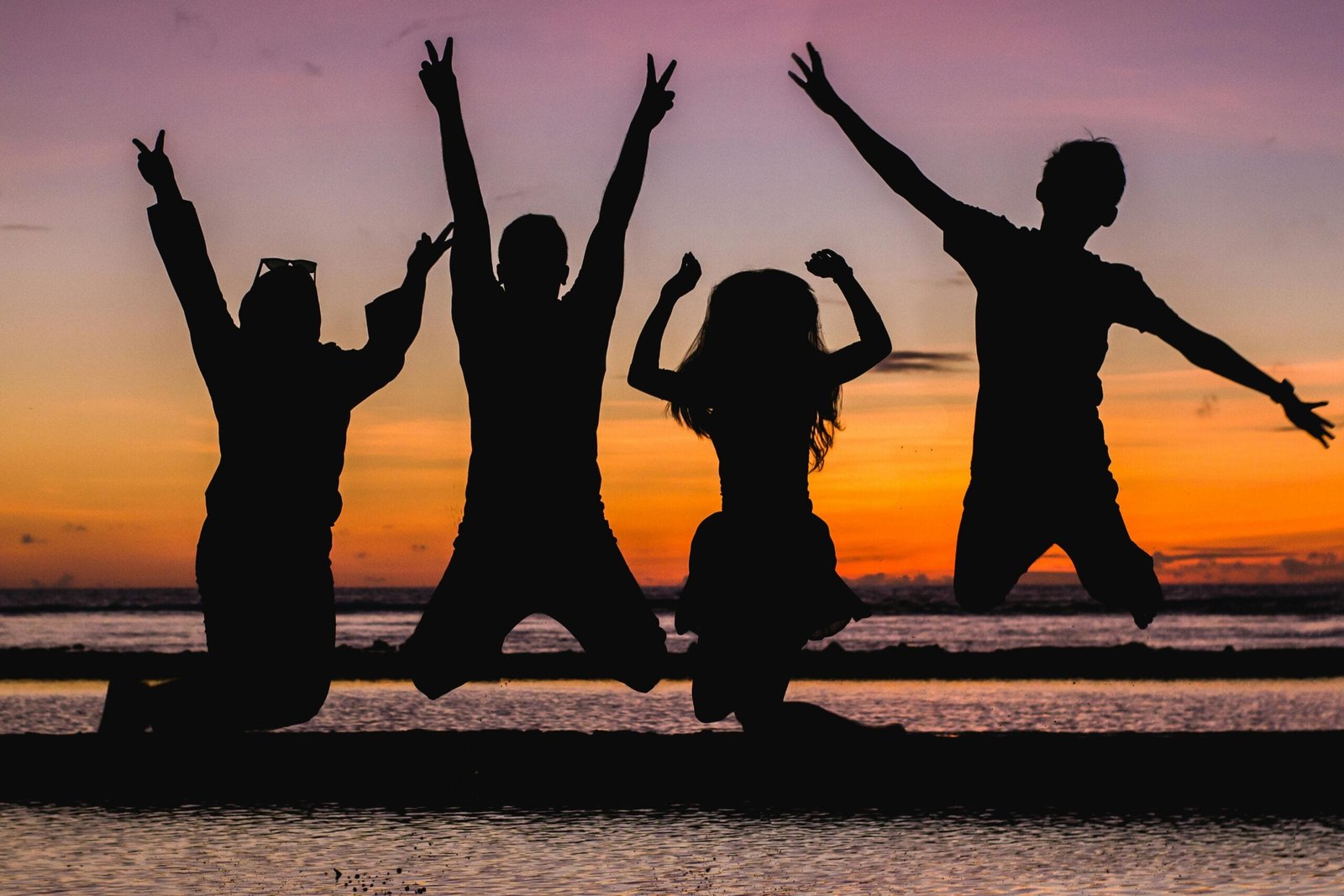 Custom Transfers 5 Silhouette of friends jumping on the beach at sunset, celebrating summer fun.