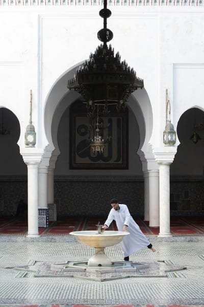 A stunning photograph capturing an ornate archway inside the complex of Moulay Idriss II's Mausoleum. The detailed stucco and Zellige tilework reflects the deep religious and historical roots of Fez and the authenticity of traditional Moroccan artistry.
