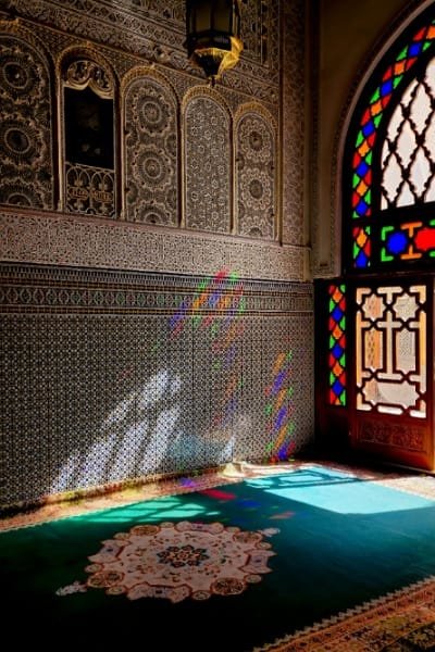 A richly decorated window or archway at the Zawiya of Sidi Ahmed Tijani in Fez, featuring intricate carved wood, detailed stucco, and Zellige tiles. The exterior architecture reflects authentic Islamic decorative arts and symbolizes the peaceful, sacred energy of Morocco’s rich Sufi heritage.