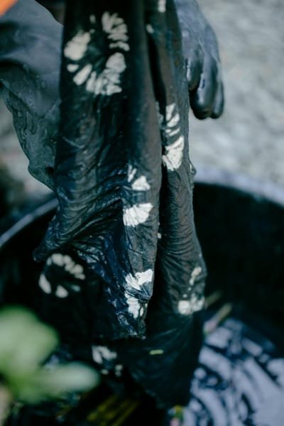 A narrow, covered alley in the Souk as-Sabbaghine (Dyeing Quarter) in Fez, where vibrant hand-dyed fabrics and clothes hang from the shops. The scene captures the ancient craftsmanship and colorful atmosphere of the traditional dyeing market.