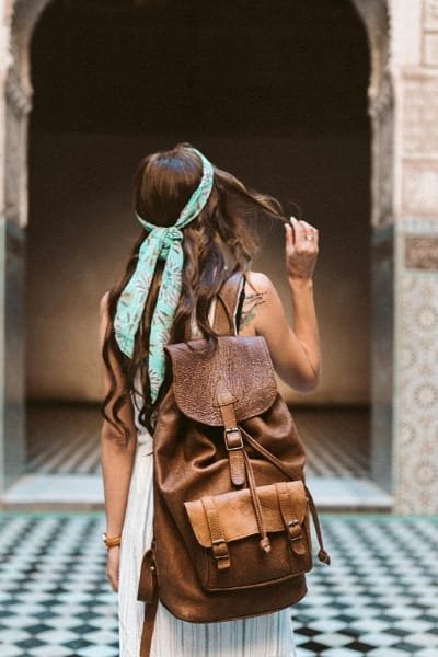 A traveler proudly wearing an authentic brown leather backpack in Morocco. This piece of leatherwork, known for its quality and durability, is typical of the handmade goods produced by Fez tanneries like Chouara Tannery.