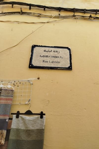 A wide, open main alley in the Fez Medina, bustling with shops and pedestrians. This street represents a rectangular-marked main road which is a reliable way to navigate toward the medina's main gates and historical landmarks.