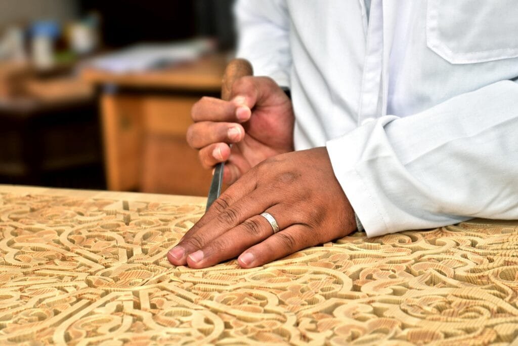 Top Things That Make Fez Special: History & Handicrafts 82 Prepare to be enchanted by the exquisite artistry of wood carving in Fez, a craft deeply ingrained in Moroccan tradition and rich with symbolism. Here, master woodcarvers possess the remarkable ability to transform the fragrant, unassuming wood of the cedar tree into breathtaking displays of intricate, hand-carved geometric patterns and flowing arabesque motifs. These stunning creations grace the architectural elements of Fez, adorning majestic doors that invite you into hidden worlds, grand ceilings that inspire awe, delicate window screens that filter the light in mesmerizing ways, and elegant traditional Moroccan furniture that speaks of heritage and comfort.This delicate art is not acquired overnight; it demands years of rigorous training, a keen eye for the smallest detail, and an innate artistic sensibility. Each carved panel is more than just decoration; it whispers a story, reflecting the profound spiritual harmony, the elegant balance of mathematical principles, and the deep-seated aesthetics of Islamic art. Whether you find it adorning the sacred space of a mosque, the opulent halls of a palace, or the tranquil ambiance of a traditional riad, the presence of meticulously carved woodwork invariably adds a layer of warmth, beauty, and profound cultural significance to every space it graces.The magic of Fez's wood carving lies in several key aspects:A Legacy of Timeless Skill: Every single piece is a testament to human artistry, carved entirely by hand. Using what appear to be simple tools, these artisans draw upon an immense reservoir of knowledge and experience passed down through generations, transforming raw material into intricate beauty.
A Symbol of Prestige and Refinement: In Moroccan culture, the presence of fine woodwork is often associated with nobility, elegance, and a deep appreciation for refined aesthetics. It speaks of heritage, taste, and a connection to the rich artistic traditions of the land.
A Living Act of Cultural Preservation: The continuation of this exquisite tradition is a testament to the dedication of the artisans who tirelessly keep this art form alive. Through the vital practice of master passing their knowledge and skills to apprentice, the legacy of Moroccan wood carving endures, ensuring its survival for generations to come.
As you explore Fez, take a moment to truly appreciate the artistry of the woodcarvers. Their work is a tangible expression of the city's soul, a beautiful reminder of the enduring power of human skill and the timeless elegance of Moroccan artistic heritage.