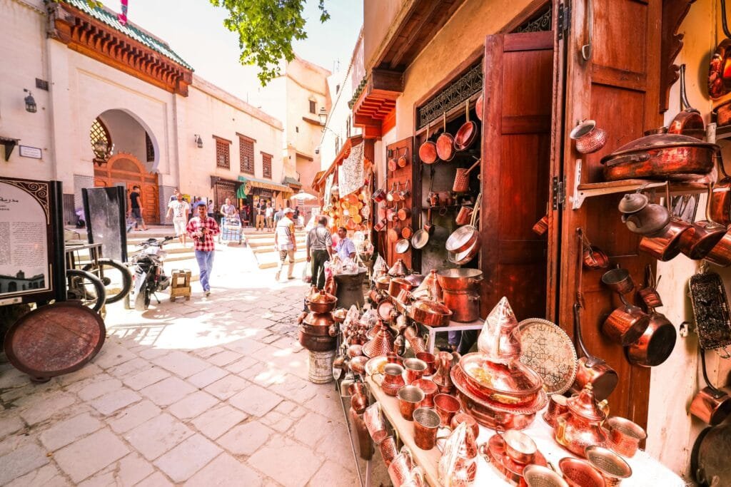 Top Things That Make Fez Special: History & Handicrafts 30 – The Heart of Knowledge and Craft in FezPlace Seffarine sits in the heart of Fez’s old medina. This historic square blends the city’s intellectual, spiritual, and artisanal traditions. This small but vibrant square is home to three of Fez’s most iconic landmarks:📚 Al-Qarawiyyin LibraryFounded in the 9th century, it is considered one of the oldest libraries in the world still in operation. It houses a priceless collection of ancient manuscripts and has long been a beacon of scholarship in the Islamic world.🏫 Seffarine MadrasaBuilt in 1271 by the Marinid dynasty, this was the first formal school for students of theology and law in Fez. Its design showcases beautiful Moroccan craftsmanship. You’ll see colorful zellij tiles, carved wood, and a peaceful central courtyard.🔨 The Coppersmiths' SoukThe square itself is named after the “saffarine” (coppersmiths) who have worked here for centuries. You hear the rhythmic sound of hammering. Artisans are handcrafting traditional copperware. This experience immerses you in Fez's living heritage.Visiting Place Seffarine takes you deep into the heart of Fez. Here, knowledge, spirituality, and craftsmanship come together beautifully.