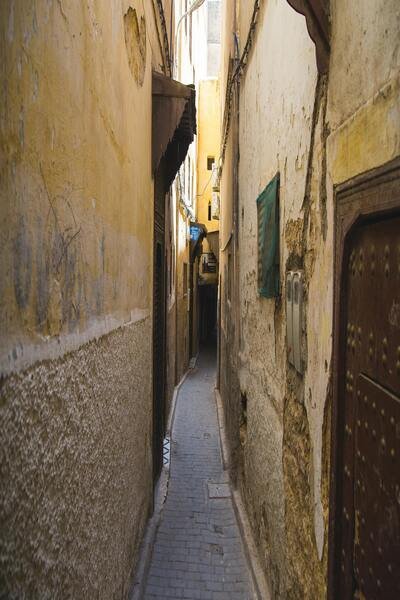 A quiet, narrow alleyway in the heart of the Fez Medina, showcasing the city's peaceful atmosphere and sense of tranquility. This image appeals to tourists looking for a safe and serene exploration experience.