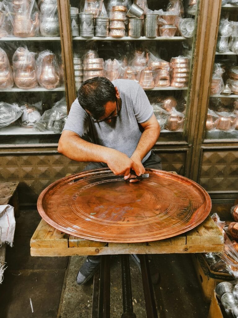 Top Things That Make Fez Special: History & Handicrafts 79 In the heart of Fez, particularly in the famous Place des Nejjarine, the tradition of brass and copper engraving has been passed down through generations. Skilled artisans, known as metalworkers, use specialized tools to carve intricate designs into sheets of copper and brass, creating everything from traditional pots to decorative pieces.The process of engraving is labor-intensive and requires precision. Artisans begin by heating the metal to make it malleable, then use chisels and hammers to create delicate geometric patterns, floral motifs, or even elaborate calligraphy. The result is a beautiful piece that reflects the expert craftsmanship and cultural heritage of Morocco.🌟 Why It’s Important:
Historical Significance: Copper and brass engraving has been a significant craft in Fez for centuries, contributing to the city’s reputation as a center of craftsmanship and trade.Unique Art: Each piece is unique, showcasing the artisan's skill and creativity, making them highly valued both locally and internationally.Cultural Legacy: The designs often carry deep meanings, reflecting Moroccan symbolism and the influence of Islamic art.