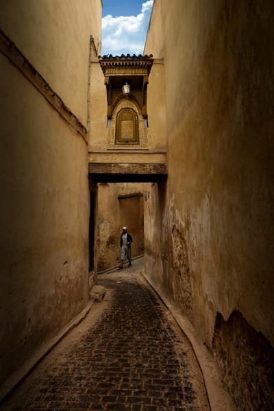 A view inside a steep, narrow alleyway (the maze) in the Fez medina, where time seems to have stopped. Several donkeys, the traditional means of transport, are carrying goods up the stone stairs. This image highlights the overwhelming yet fascinating nature of the city's labyrinthine layout and the need for a local guide.