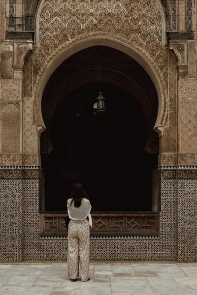 A beautifully detailed Moroccan archway with intricate stucco and Zellij tile work in Fez, symbolizing the city's 1,200 years of continuous history and its status as a "living museum". The architectural richness requires a guide to appreciate its full historical context.