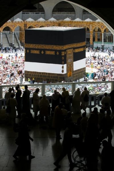 Aerial view of the Holy Kaaba in Mecca, Saudi Arabia, surrounded by a multitude of Muslim pilgrims during the Hajj season. The image captures the profound spiritual significance and scale of the pilgrimage.