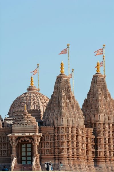 A close-up view of the intricately carved towers (gopuram) of a Hindu temple, symbolizing the complex spiritual and traditional importance of these sites. The image is used to discuss the restriction of entry to non-practicing Hindus to preserve religious purity.