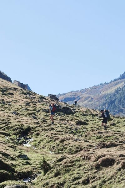 Hikers ascending a steep, grassy hill in the High Atlas Mountains of Morocco. Represents the ultimate hiking destination that beckons you to go on life-changing adventures through fragrant cedar forests and hidden waterfalls.