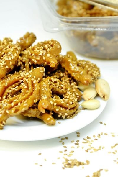 A plate of traditional Moroccan Chebakia (flower-shaped, deep-fried dough) dipped in honey and sprinkled with sesame seeds, often eaten during Ramadan.