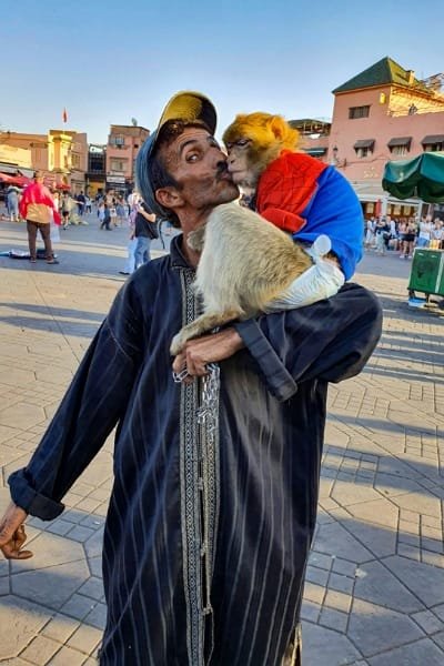 A foreign traveler and a young Moroccan child playing in front of a traditional Bedouin tent in the desert. This represents the simple, kind people who make a stay enjoyable and create beautiful memories, encouraging participation in local life.