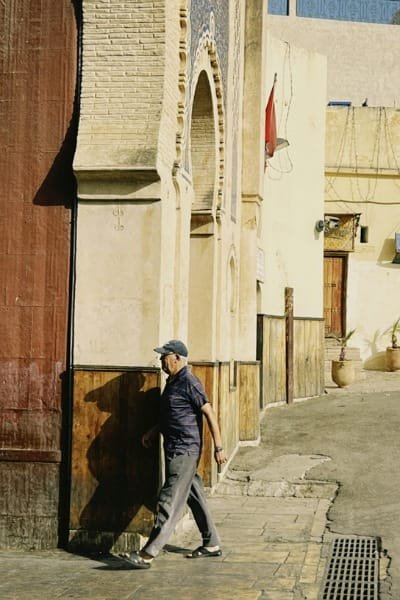 A smiling female tourist sitting outdoors, looking over a coastal landscape. This image symbolizes the smooth and enjoyable journey facilitated by Morocco's robust infrastructure, making it an accessible destination for relaxation and cultural experiences.