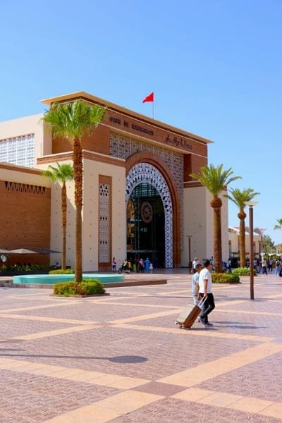 The modern, grand façade of a Moroccan railway station (likely Marrakech or Rabat), symbolizing the efficient ONCF network and the "Al Boraq" high-speed train, Africa's first, connecting Tangier, Rabat, and Casablanca.