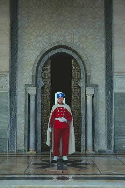 A member of the Royal Guard (representing Morocco's effective security apparatus) standing vigilantly at a palace entrance. This image reflects the robust security and visible police presence in tourist areas, ensuring a safe environment for visitors.