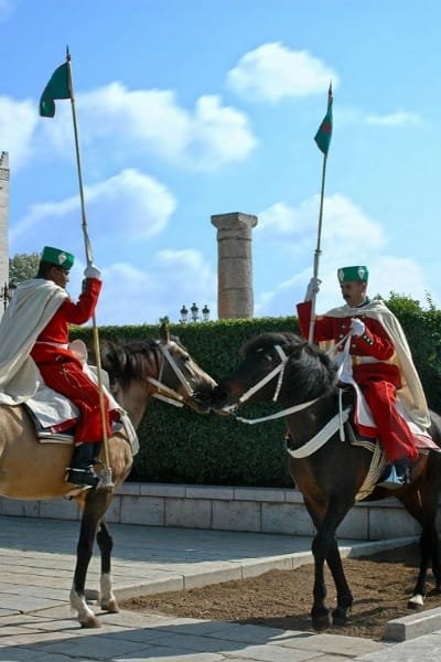 Two Royal Guards on horseback in traditional red and white uniforms, symbolizing the high degree of safety and stability in Morocco. This commitment to security allows visitors to fully immerse themselves in the rich cultural experiences without worry.