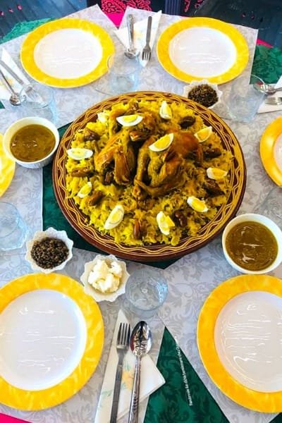 A close-up of traditional Moroccan Couscous served in an ornate bowl, topped with tender vegetables (carrots, zucchini) and a rich, savory sauce. This dish represents the delicate and central role of Moroccan cuisine.