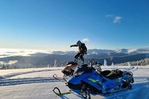 Tourist enjoying an adventure snowmobile tour in a snowy Moroccan mountain landscape.