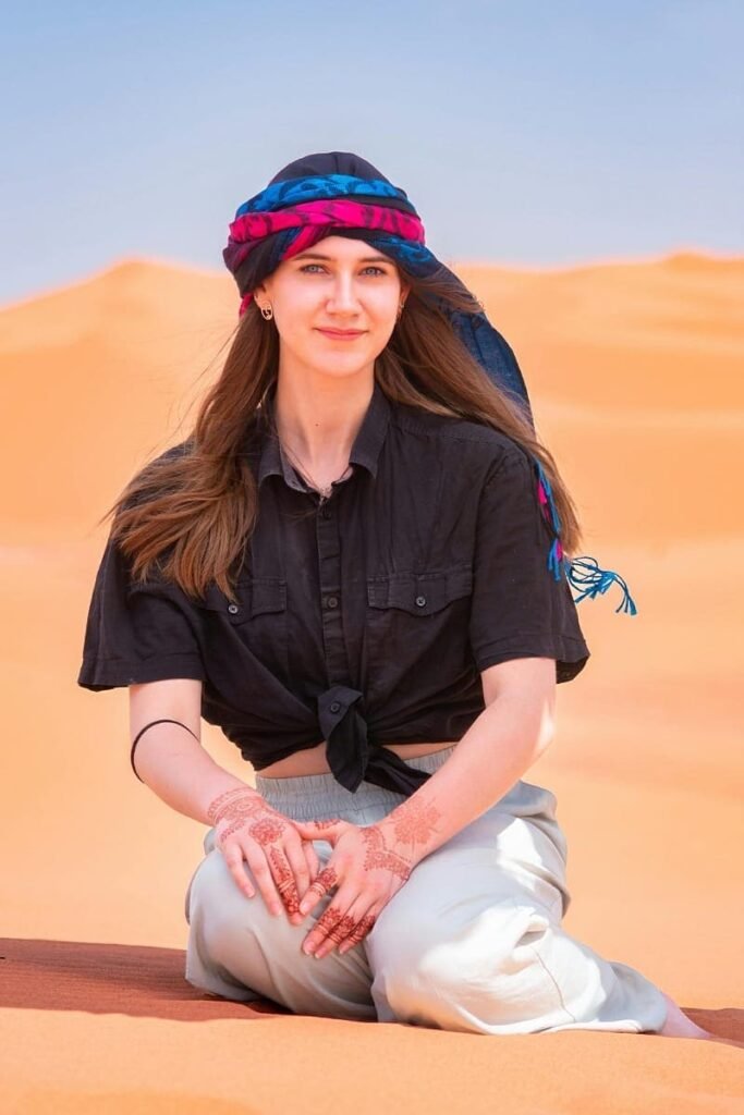 Female traveler sitting in the Merzouga desert, symbolizing a customized private Morocco tour.