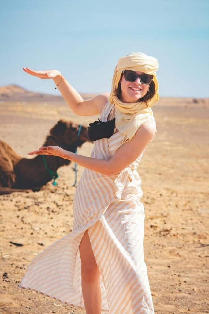 Happy female tourist posing with a camel on a Fez to Sahara Desert tour.