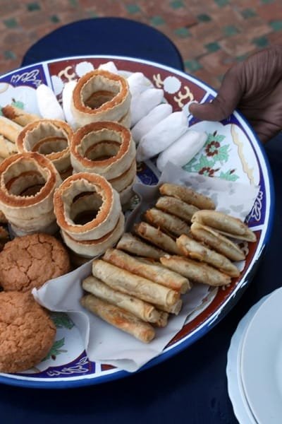 A platter of diverse Moroccan traditional sweets, including Chebakia-style pastries and biscuits, served on a colorful plate, highlighting the dessert stop on the Fes food tasting tour.